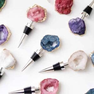 Assorted wine bottle stoppers with colorful geode tops arranged on a white background.