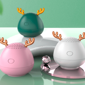 Three colorful, egg-shaped speakers with decorative reindeer antlers on a reflective surface against a green background.