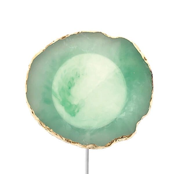 A polished green agate slice on a metal stand, with a translucent center and rough, uneven gold-toned edges.