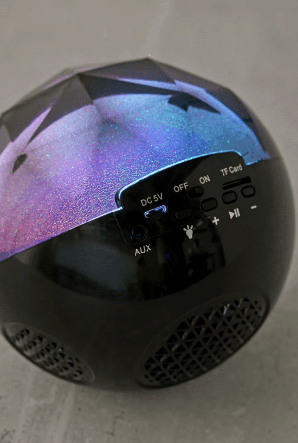 Multicolored galaxy projector on a gray surface, displaying various control buttons for power, volume, and connectivity options including aux and tf card.