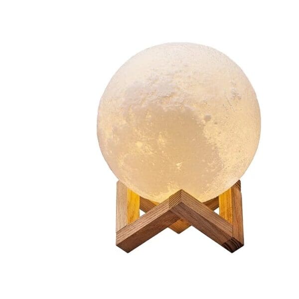 A glowing moon lamp sits on a wooden stand against a white background.