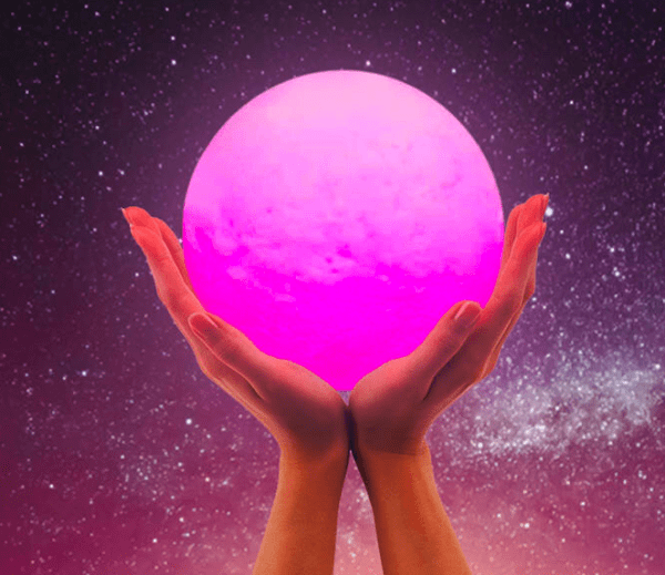 Two hands cradling a glowing pink orb against a starry purple sky.