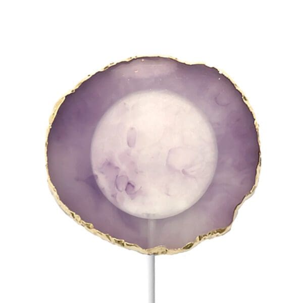 A purple and white agate slice lollipop with a gold trim on a white background.