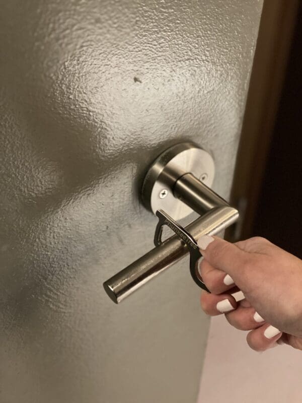 A person's hand using a key to unlock a modern silver door handle on a textured gray door.