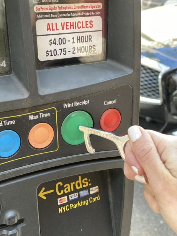 A hand inserting a key into a parking meter's card slot, buttons indicating payment options above.
