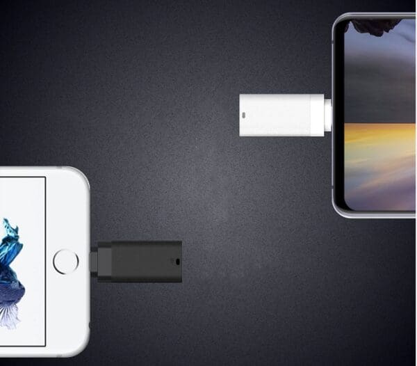 Two smartphones and two usb adapters on a dark surface, suggesting data transfer or charging setup.
