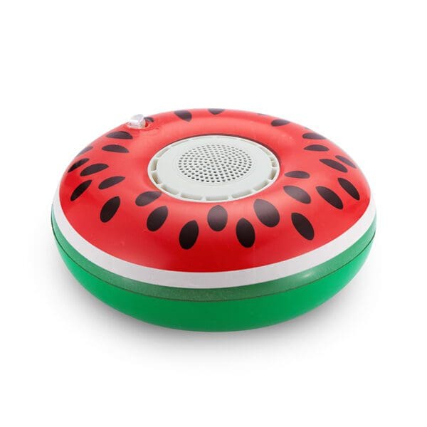 A portable speaker designed to look like a slice of watermelon, featuring a red top with black seeds and a green base, isolated on a white background.