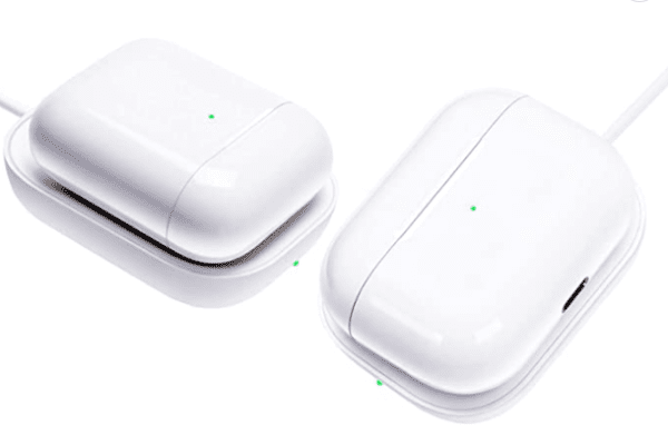 Two white electronic devices, possibly wireless earbuds in their charging cases, connected to charging cables with green indicator lights on.