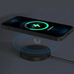 Smartphone charging wirelessly on a circular pad, displaying a charging icon on its screen, with visible blue electromagnetic waves.