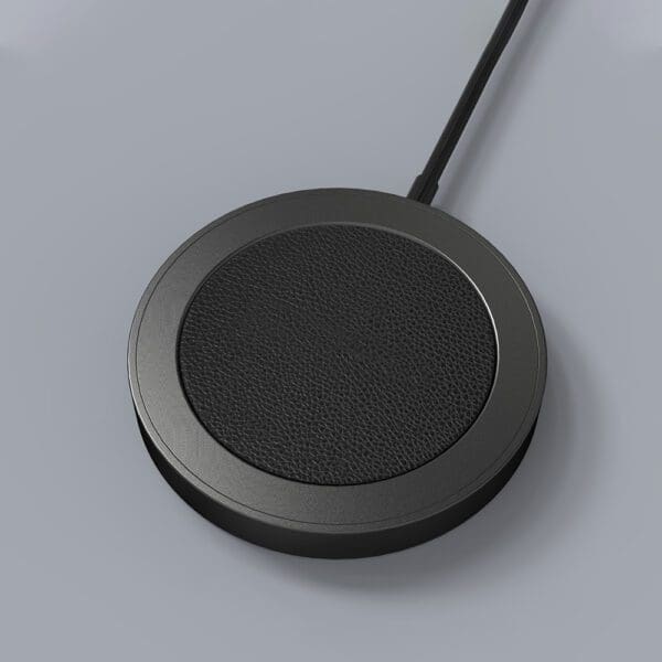 A black, round wireless charging pad with a textured surface and a cable, on a gray background.