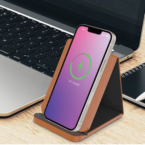 A phone sitting on top of a desk next to a laptop.