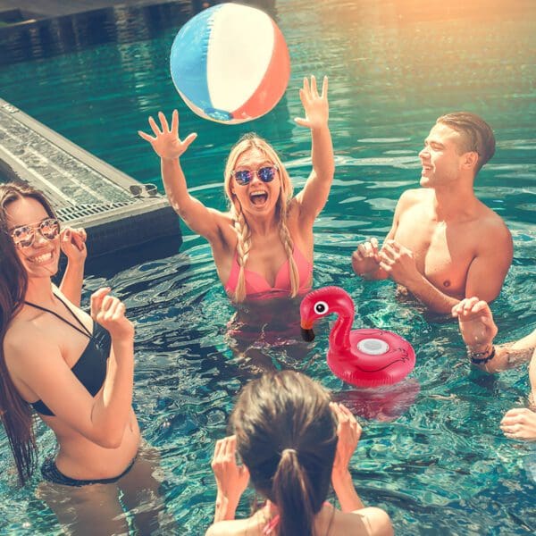 Four friends enjoying a sunny day in a pool, playing with a colorful beach ball and a flamingo floatie.