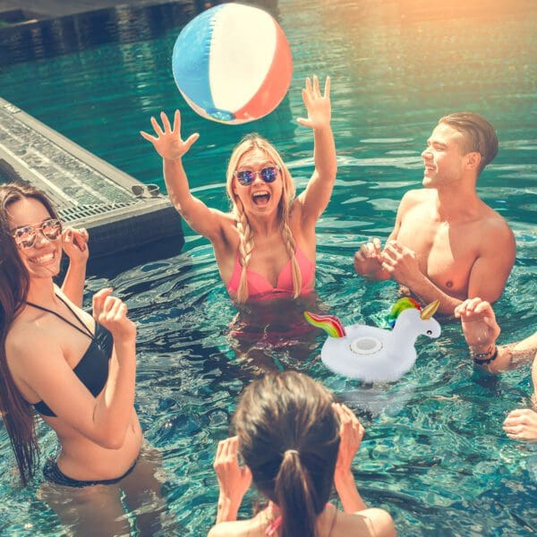 Group of young adults enjoying a sunny day in a pool, playing with a beach ball and inflatable rings.