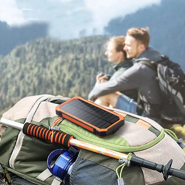 Portable solar charger on a backpack with a couple looking at a mountainous landscape in the background.