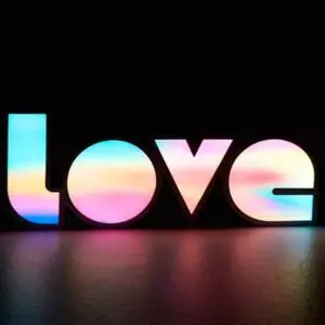 A decorative sign spelling "love" with multicolored lighting against a dark background.