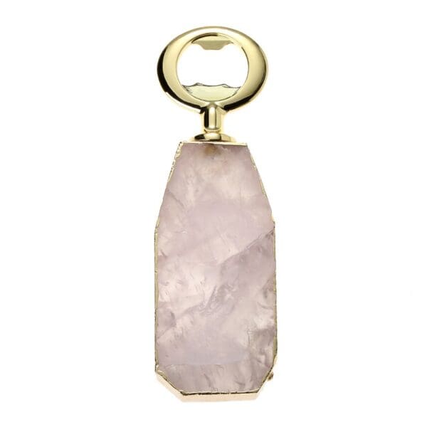 Gold bottle opener with a rough-cut, pink crystal handle, isolated on a white background.