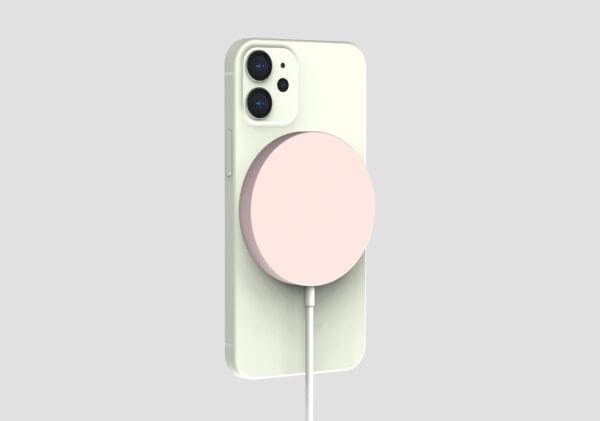 A smartphone with a light pink magnetic charging puck attached to its back, against a neutral gray background.