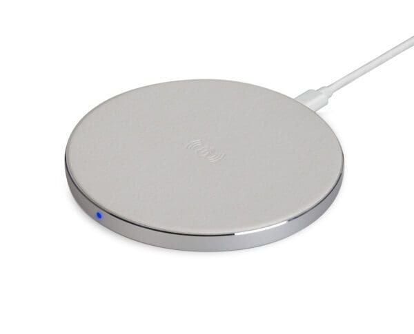 Silver wireless charging pad with a blue indicator light connected by a white cable, isolated on a white background.