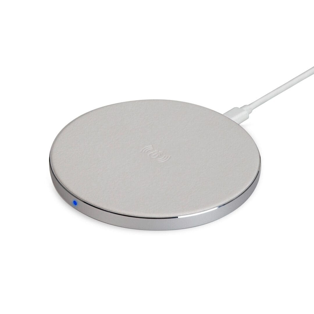 A silver wireless charger sitting on top of a white surface.