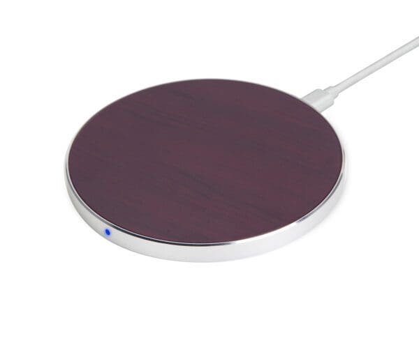 A purple wireless charging pad with a silver edge and led indicator, connected to a white cable, on a plain white background.
