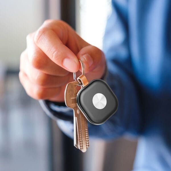 A person holding a set of keys with a Tag Tracker (2 Pack) attached, utilizing the Apple Find My network, close-up.