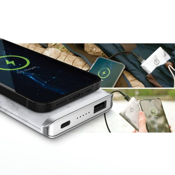 A Grey - Leather 5K Wireless Charging Power Bank charging three smartphones simultaneously, placed on various surfaces including a towel and a backpack.