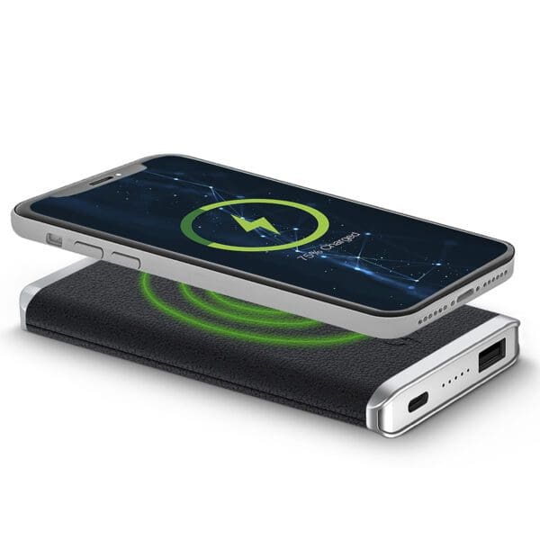 Smartphone lying on a Leather Wireless Charging Power Bank with a glowing green light, indicating charging in progress.