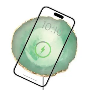 Smartphone displaying a charging battery icon over a green abstract wallpaper, centered with battery level and time visible on a Wireless Charging Crystal Pad.