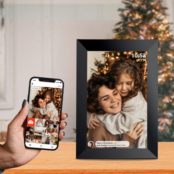 A photo of a phone displaying an image of a mother and daughter hugging beside a Christmas tree, with a Digital Picture & Video Frame beside it.