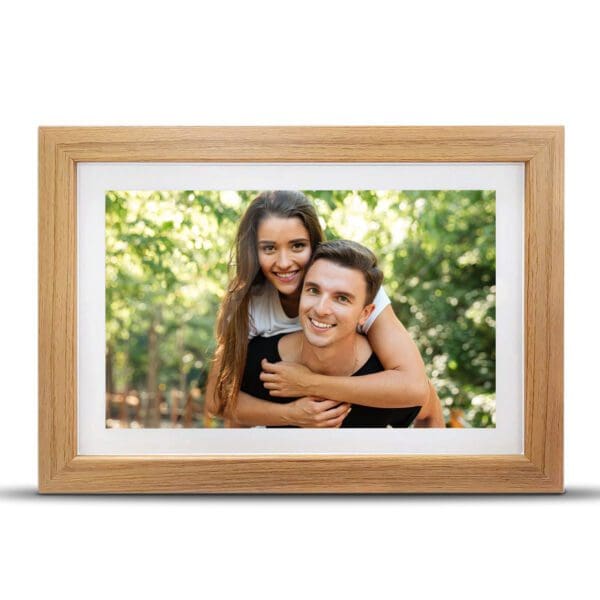A Digital Picture & Video Frame of a smiling young couple, with the woman piggybacking on the man, set against a blurred green outdoor background.