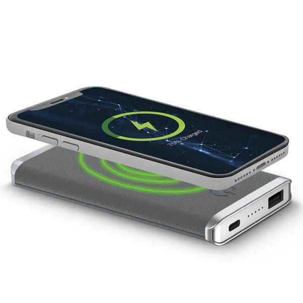 Smartphone resting on a Leather Wireless Charging Power Bank, displaying a battery charging icon on its screen.