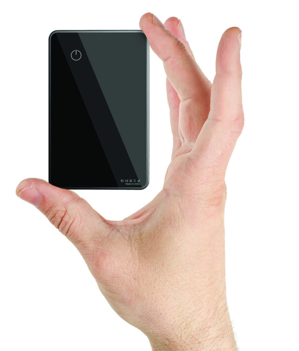 A hand holding a small, off black Card Tracker with a circular power button on top and a subtly reflective screen.