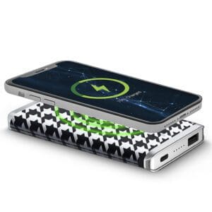 Smartphone charging on a Houndstooth - Leather 5K Wireless Charging Power Bank with a visible green battery indicator.