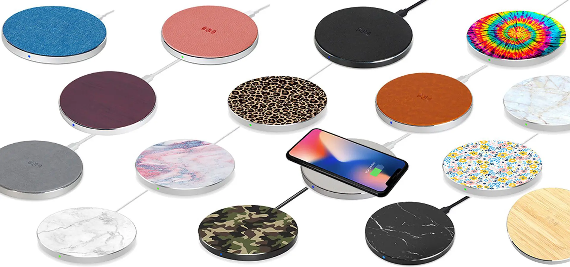 A collection of wireless charging pads in various colors and patterns, including a phone charging on one of the pads.
