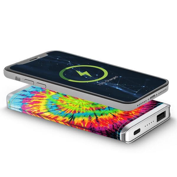 Smartphone lying on top of a colorful tie-dye fabric, displaying a starry night wallpaper and connected to a Leather Wireless Charging Power Bank.