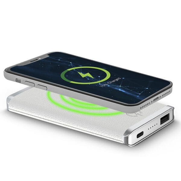 Smartphone charging on a Leather Wireless Charging Power Bank, displayed at an angle, with a visible charging symbol on the screen.