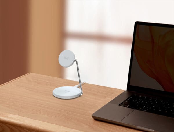 Wireless charging stand with laptop on desk.